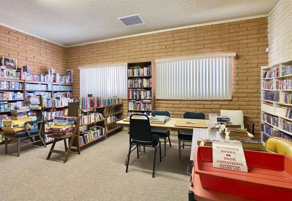 Library room with chairs and long tables and books in tall wooden shelves in the background