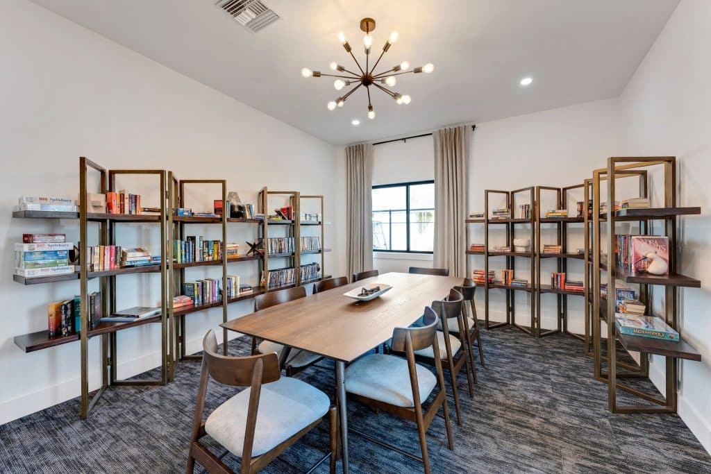 A modern conference room with bookshelves on the walls, a long wooden table surrounded by chairs, and a chandelier hanging from the ceiling in mesa az